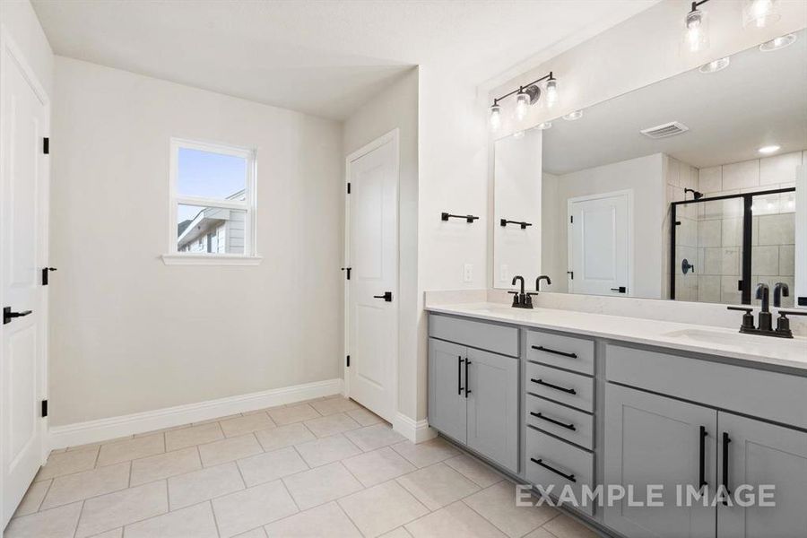 Bathroom featuring tile patterned floors, a shower with door, and vanity