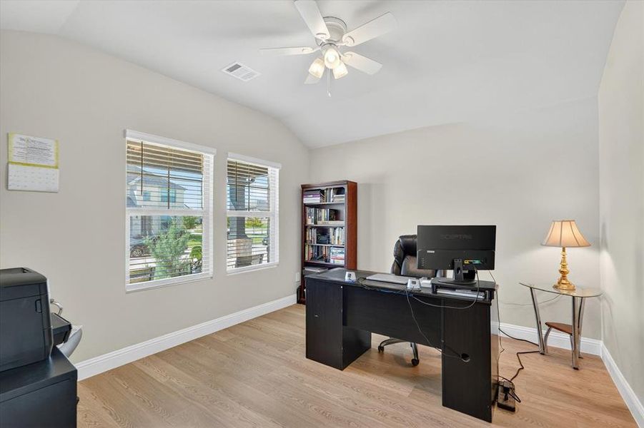 Spacious room featuring wood-finish flooring, vaulted ceilings, and a ceiling fan with integrated lighting Spacious room featuring wood-finish flooring, vaulted ceilings, and a ceiling fan with integrated lighting