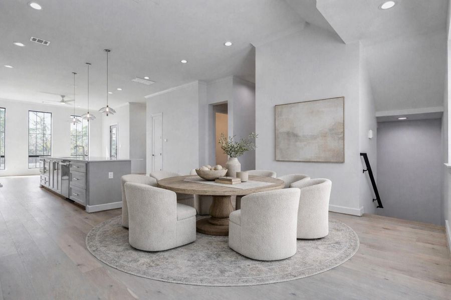 Bright and spacious dining area seamlessly integrated into the open-concept second floor of this contemporary Memorial townhome. Engineered wood flooring, recessed lighting, and modern pendant fixtures create an inviting setting for everyday meals or entertaining guests. Positioned between the chef’s kitchen and living area, the space offers effortless flow while large windows bring in natural light and views of the surrounding neighborhood. This photo has been virtually staged for visual reference.