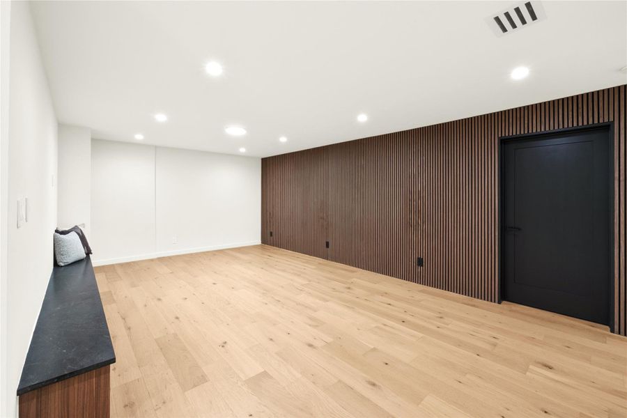 lower level area featuring recessed lighting, light wood-style floors, and wood walls