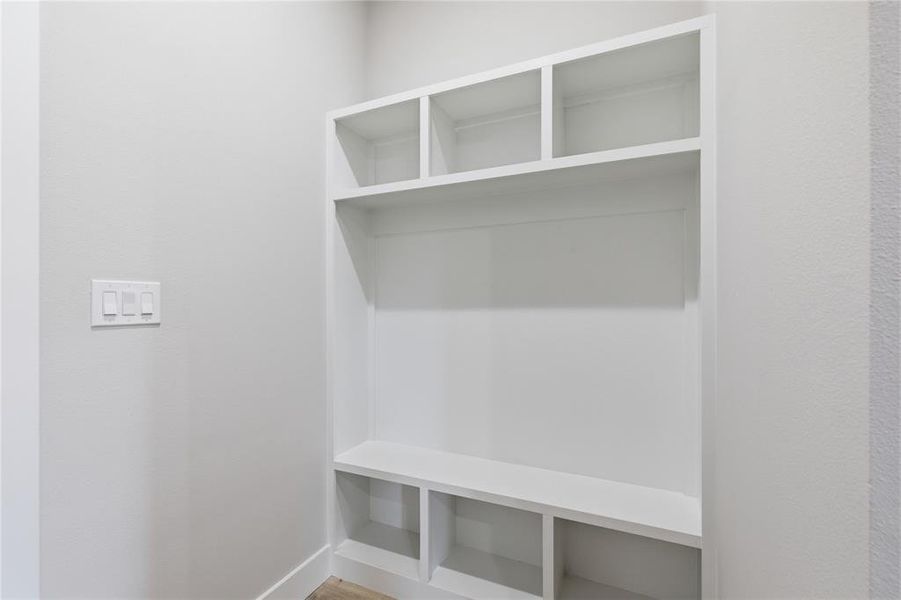 Built-in white shelving unit with varied cubby sizes, a broad central shelf, and lower compartments