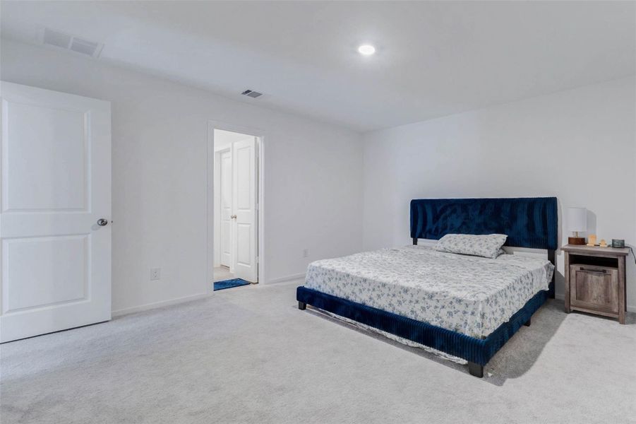 Generously sized primary suite with plush carpeting, abundant natural light, and plenty of room for a king-size bed and additional furniture.