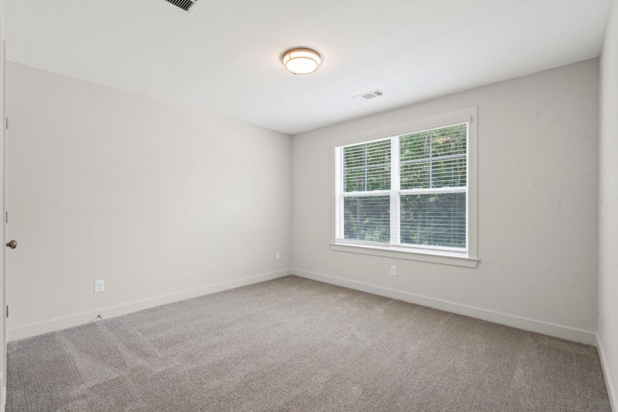 Neutral-toned room featuring a large window with blinds, light gray wall paint, and gray carpeting Neutral-toned room featuring a large window with blinds, light gray wall paint, and gray carpeting