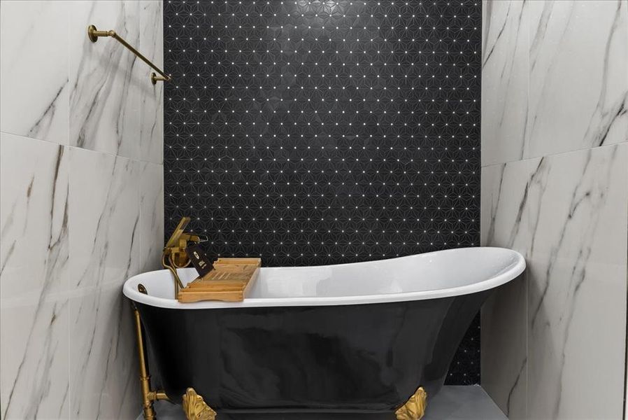 Gold Clawfoot onyx free-standing tub with black accent wall