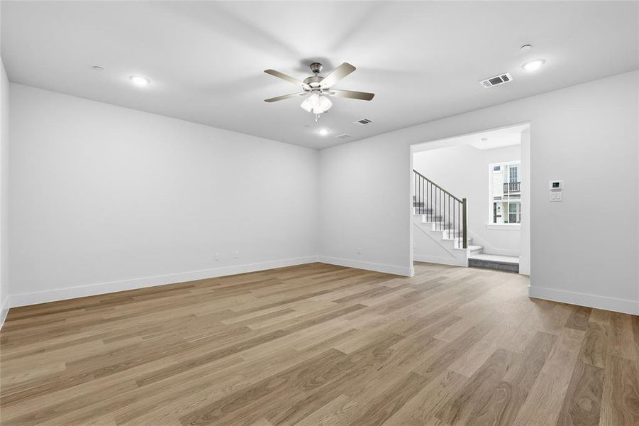 Spacious living area featuring light wood flooring, recessed lighting, and a ceiling fan