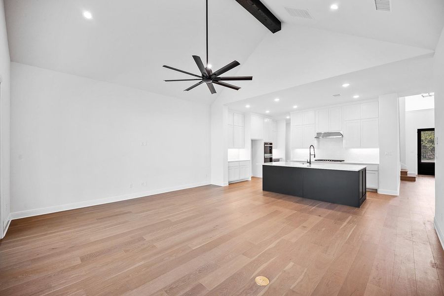 Living area featuring high vaulted ceiling, beam ceiling, light wood-style floors, recessed lighting, and baseboards Living area featuring high vaulted ceiling, beam ceiling, light wood-style floors, recessed lighting, and baseboards