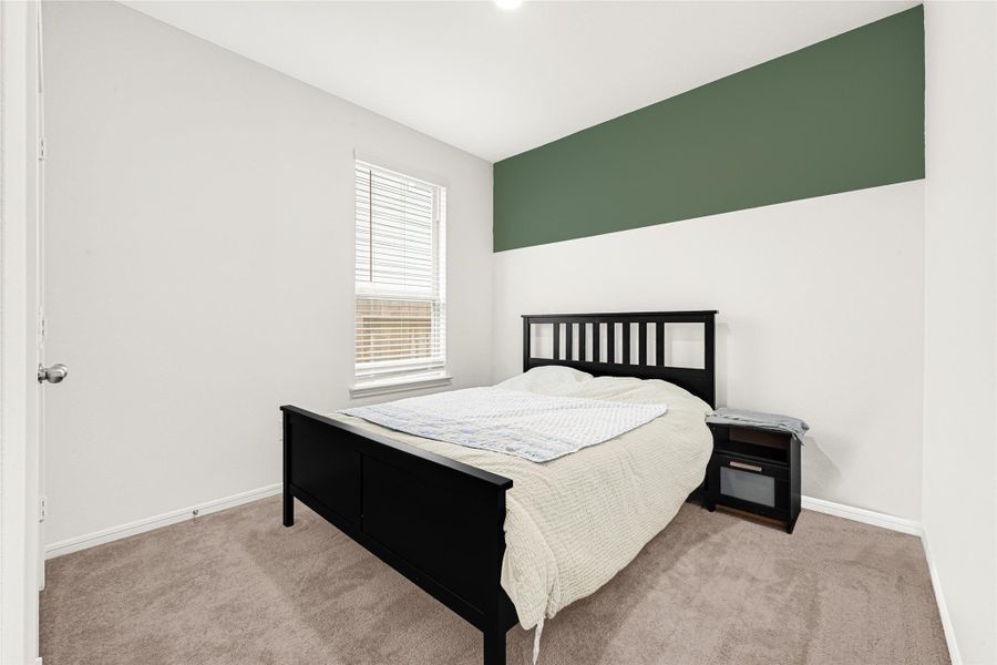 Beautifully styled bedroom highlighting a dark wood headboard and a subtle green accent wall.
