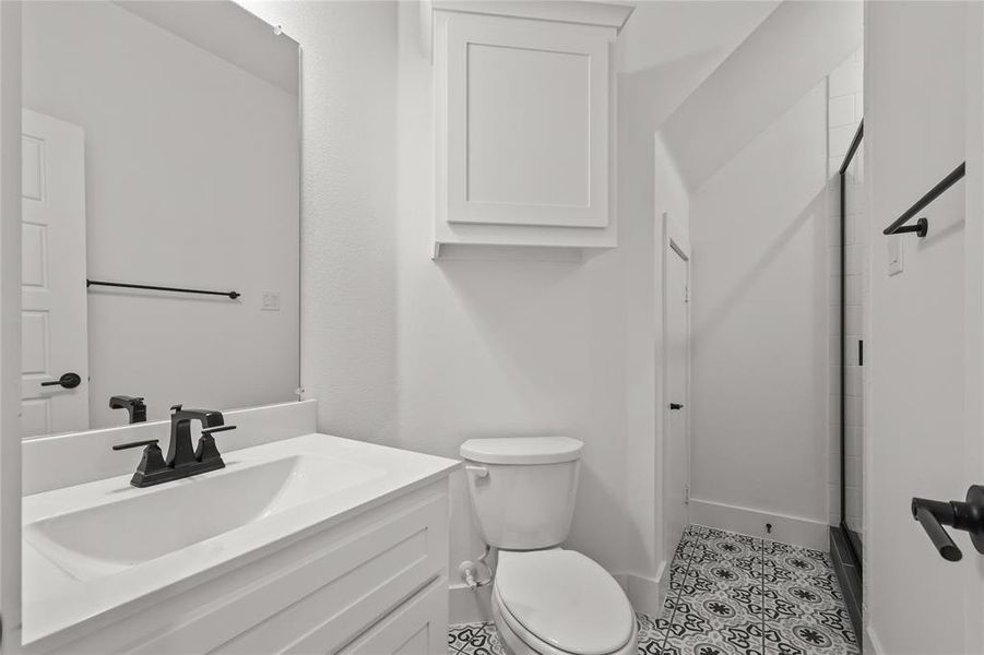 Bathroom featuring a shower with door, vanity, toilet, and tile patterned floors