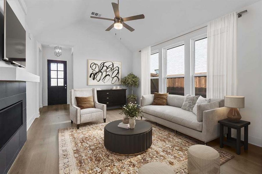 Living area featuring wood finished floors, lofted ceiling, a ceiling fan, and a fireplace Living area featuring wood finished floors, lofted ceiling, a ceiling fan, and a fireplace