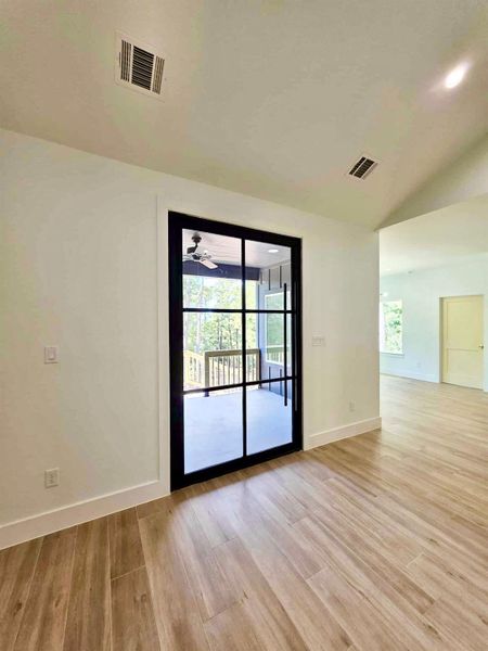 Empty room with vaulted ceiling and light wood-style flooring