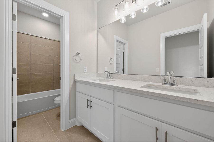 Full bath featuring double vanity, light tile patterned floors, and shower / bath combination