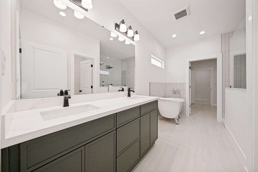 A well-lit primary bathroom featuring a double vanity, a freestanding soaking tub, and a spacious glass-enclosed shower. A well-lit primary bathroom featuring a double vanity, a freestanding soaking tub, and a spacious glass-enclosed shower.