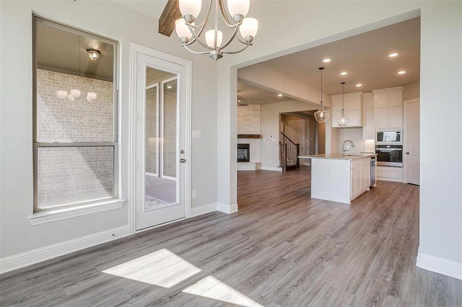 Kitchen featuring appliances with stainless steel finishes, light wood-type flooring, a kitchen island with sink, pendant lighting, and white cabinetry