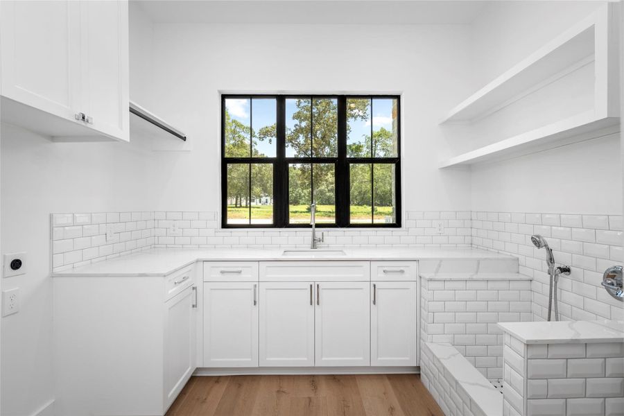 Spacious utility room with quartz countertops, a utility sink, and a custom-tiled dog wash station. Spacious utility room with quartz countertops, a utility sink, and a custom-tiled dog wash station.