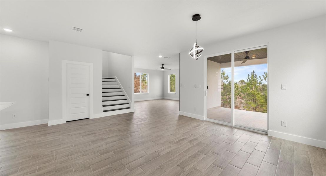 Unfurnished dining area featuring wood finish floors, stairs, and a ceiling fan