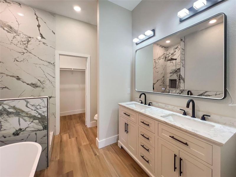 Bathroom featuring double vanity, wood finished floors, a soaking tub, and a sink Bathroom featuring double vanity, wood finished floors, a soaking tub, and a sink
