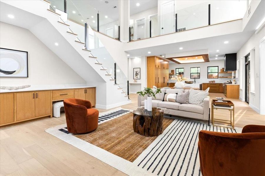 Living room with a high ceiling and light hardwood / wood-style floors