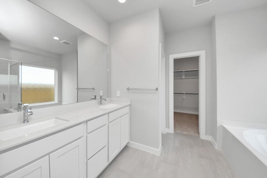 Escape to a spa-like oasis in this primary bathroom. Enjoy a walk-in shower with tile surround, a separate garden tub with custom detailing, and an elegant vanity featuring light countertops, modern hardware, and beautiful recessed lights. Experience luxury and relaxation in every detail. Sample photo of completed home with similar floor plan. Actual colors and selections may vary. Escape to a spa-like oasis in this primary bathroom. Enjoy a walk-in shower with tile surround, a separate garden tub with custom detailing, and an elegant vanity featuring light countertops, modern hardware, and beautiful recessed lights. Experience luxury and relaxation in every detail. Sample photo of completed home with similar floor plan. Actual colors and selections may vary.