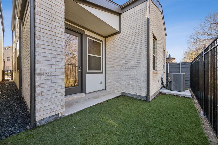 View of exterior entry with a yard and central air condition unit