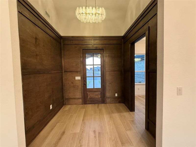 Doorway to outside featuring wood finished floors, a chandelier, and lofted ceiling Doorway to outside featuring wood finished floors, a chandelier, and lofted ceiling