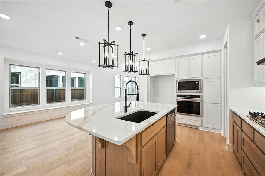 Kitchen featuring an island with sink, light wood-style floors, hanging light fixtures, recessed lighting, and stainless steel appliances Kitchen featuring an island with sink, light wood-style floors, hanging light fixtures, recessed lighting, and stainless steel appliances