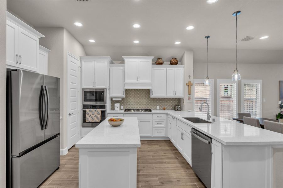 Endless quartz countertops, ample lighting, and stainless appliances highlight this chef's kitchen. A breakfast bar allows for extra seating. Endless quartz countertops, ample lighting, and stainless appliances highlight this chef's kitchen. A breakfast bar allows for extra seating.