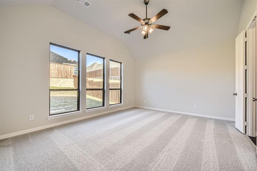 Spare room featuring carpet flooring, ceiling fan, and vaulted ceiling