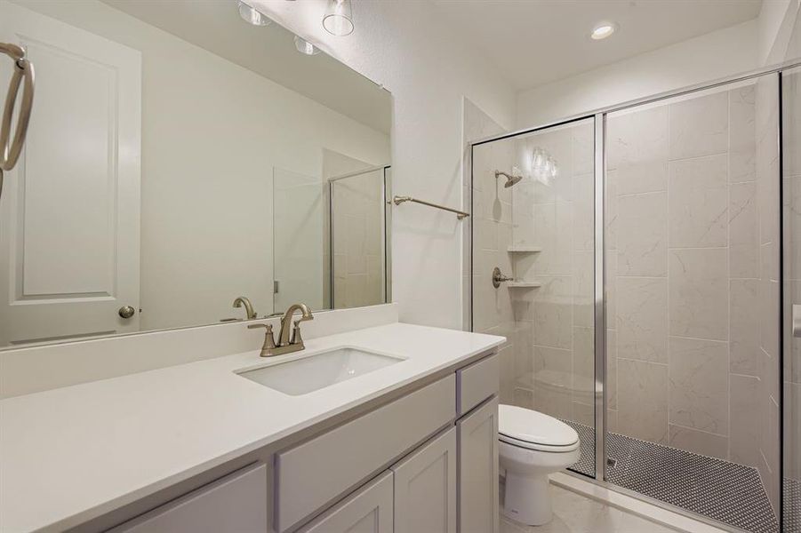 Bathroom with a shower stall, vanity, and recessed lighting