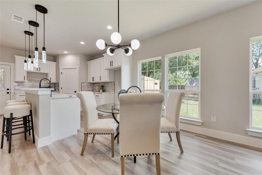 Dining area featuring an inviting chandelier, light wood-type flooring, and a wealth of natural light