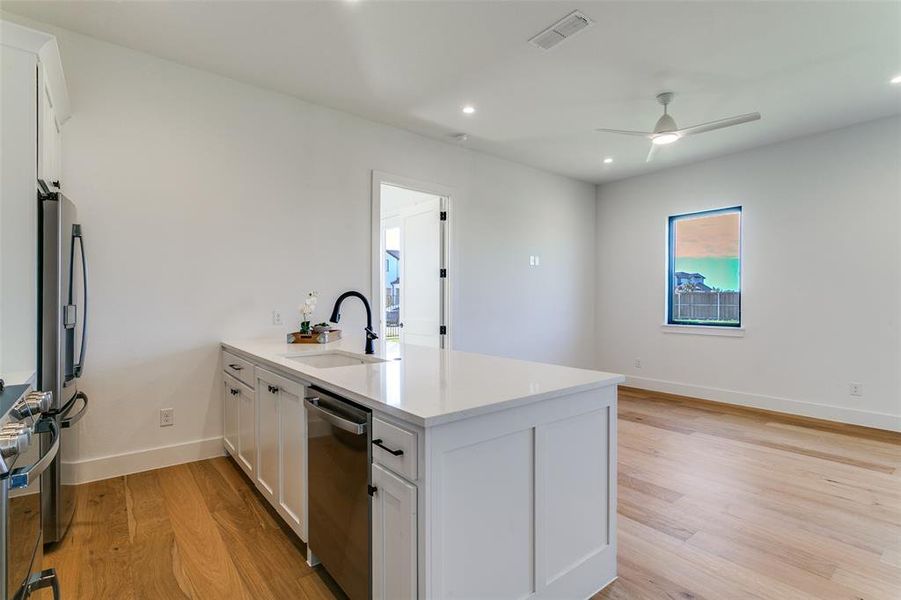 Kitchen with a peninsula, white cabinetry, recessed lighting, light wood-style flooring, and light stone counters