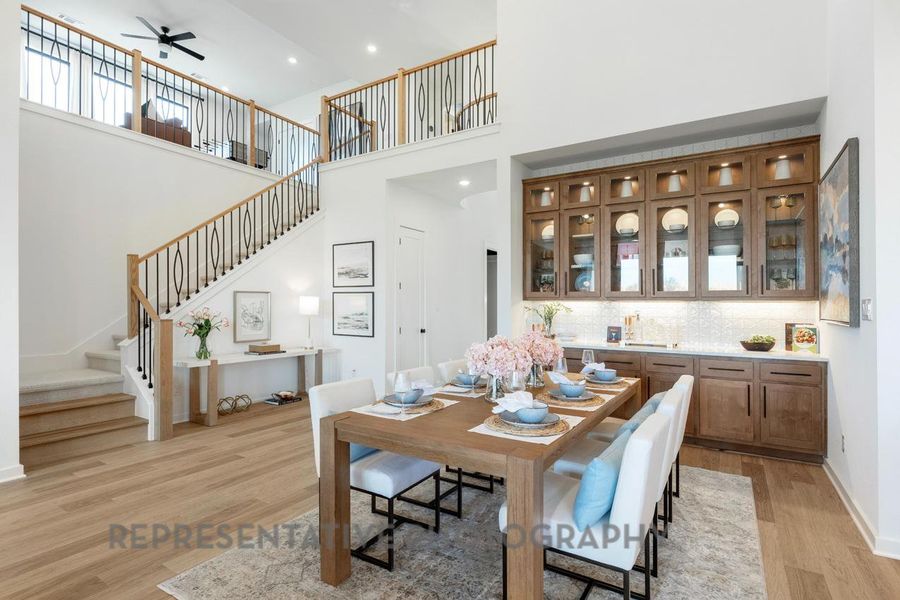 Dining space with stairs, a ceiling fan, light wood-type flooring, a towering ceiling, and recessed lighting