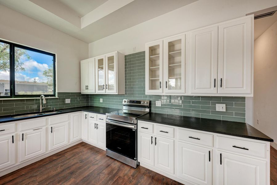 White cabinetry and dark countertops contrast beautifully against a stylish tiled backsplash.