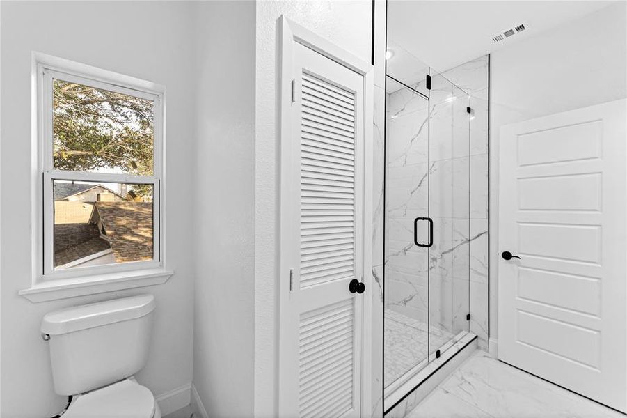 Bathroom with toilet and a shower with shower door