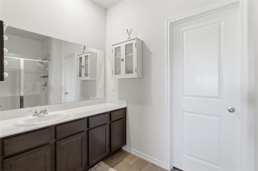 Full bath with vanity, light wood-type flooring, and a stall shower Full bath with vanity, light wood-type flooring, and a stall shower