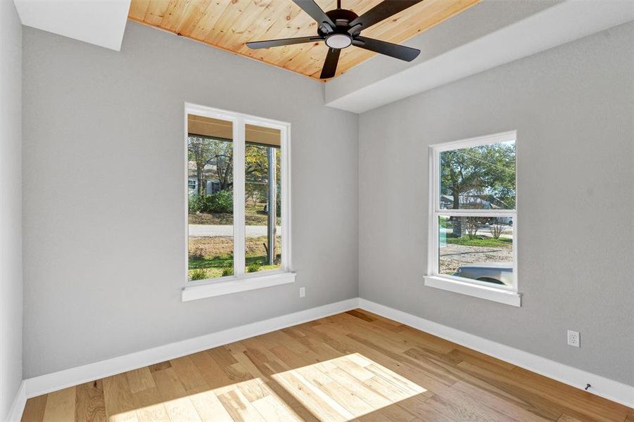 Empty room featuring light wood-type flooring, plenty of natural light, wood ceiling, and ceiling fan Empty room featuring light wood-type flooring, plenty of natural light, wood ceiling, and ceiling fan