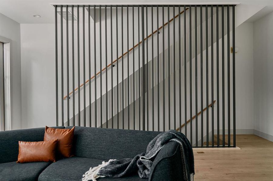 Modern architectural screen creating a distinct space, featuring vertical black slats and a light wood-finish handrail Modern architectural screen creating a distinct space, featuring vertical black slats and a light wood-finish handrail