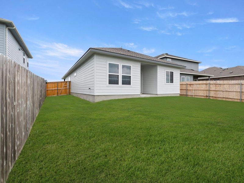A well-maintained lawn provides ample space for outdoor activities, enclosed by a privacy fence.