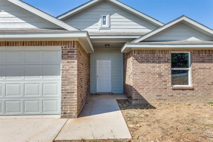 Entrance to property with brick siding and a garage
