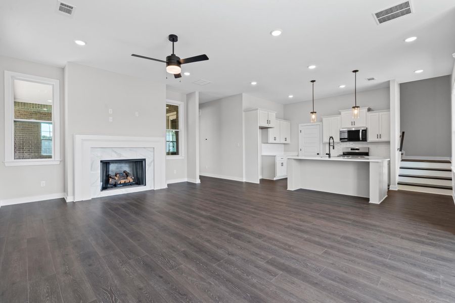 Unfurnished living room featuring a ceiling fan, dark wood finished floors, a premium fireplace, plenty of natural light, and recessed lighting Unfurnished living room featuring a ceiling fan, dark wood finished floors, a premium fireplace, plenty of natural light, and recessed lighting