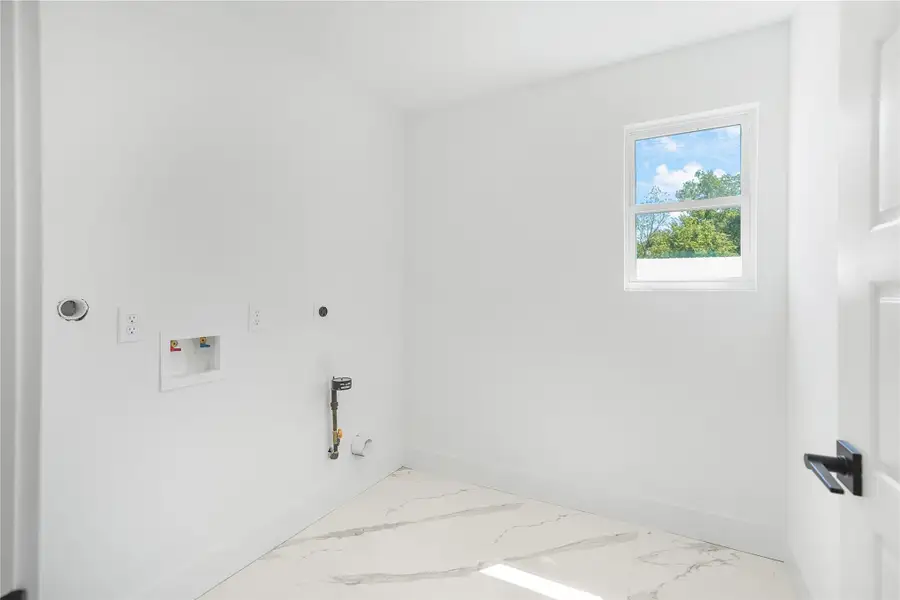 Bright and spacious laundry room featuring elegant marble-style flooring and a sunlit window, ready for your appliances. Bright and spacious laundry room featuring elegant marble-style flooring and a sunlit window, ready for your appliances.