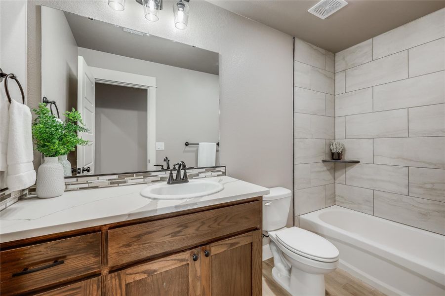 Secondary bathroom with tall vanity, shower / bathtub combo and finished tile edging