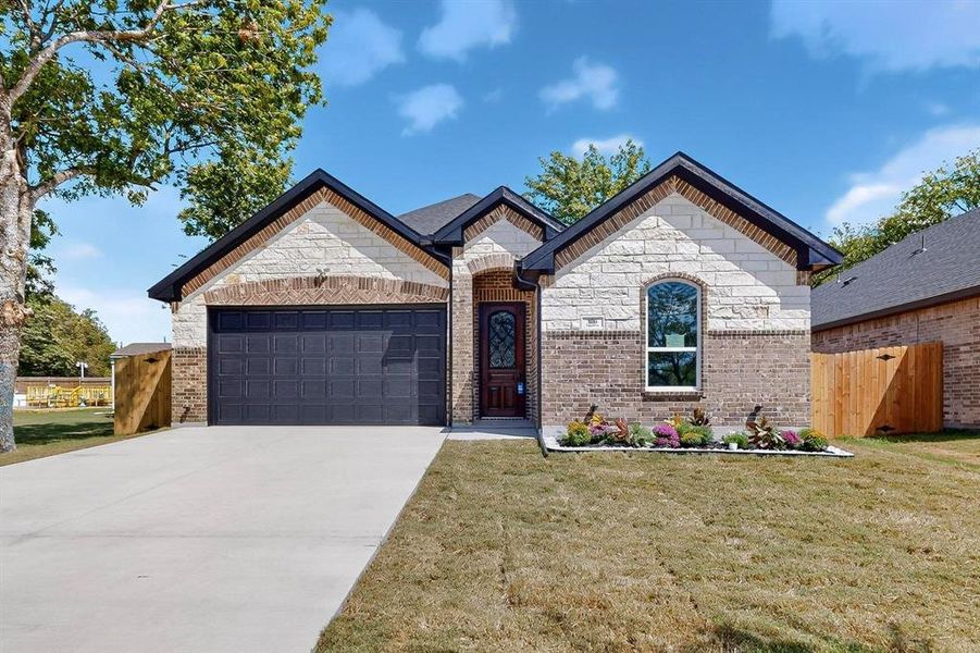 French country home with driveway, brick siding, and an attached garage