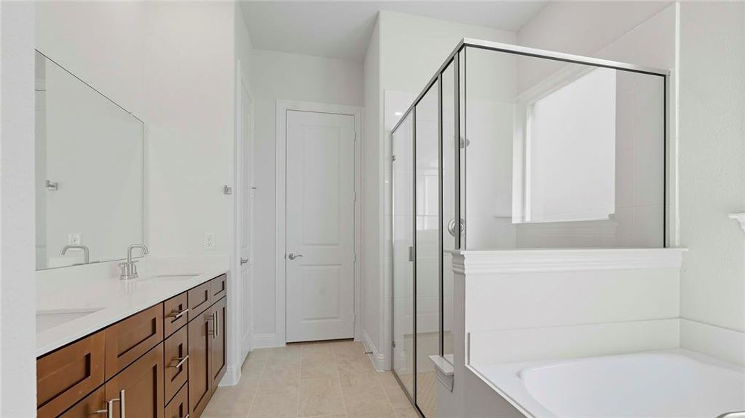 Full bath featuring double vanity, a stall shower, and a bath