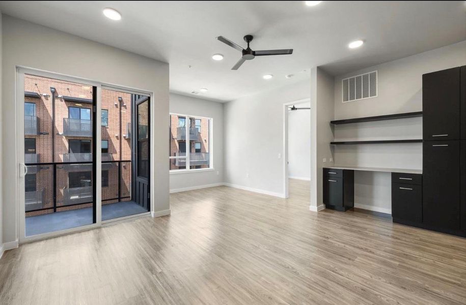 Sliding glass doors open to a private balcony, highlighting the modern wood flooring. Sliding glass doors open to a private balcony, highlighting the modern wood flooring.