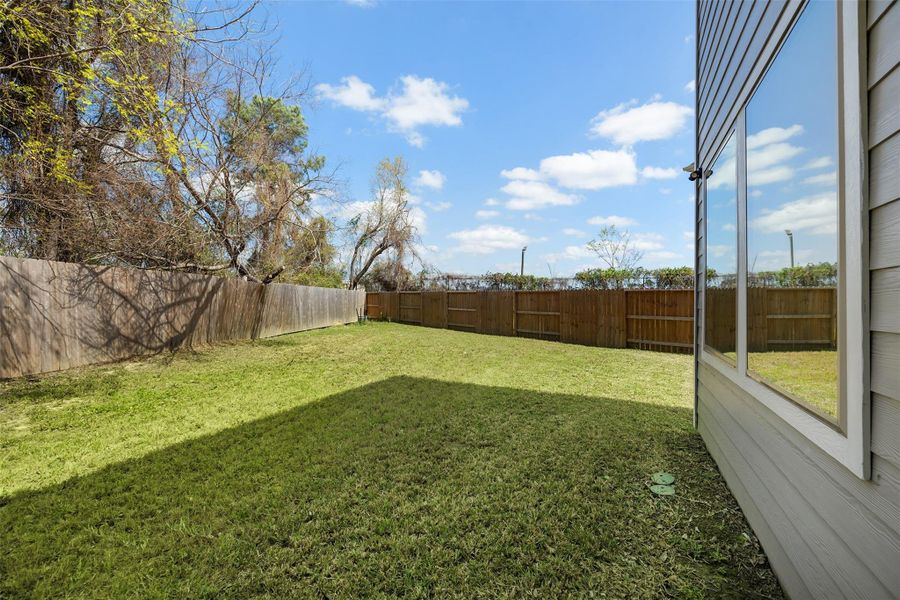 The fully fenced backyard offers both privacy and a peaceful setting, perfect for hosting gatherings or enjoying quiet moments. A row of trees along the back fence adds extra shade and enhances security, creating an inviting and tranquil outdoor retreat.