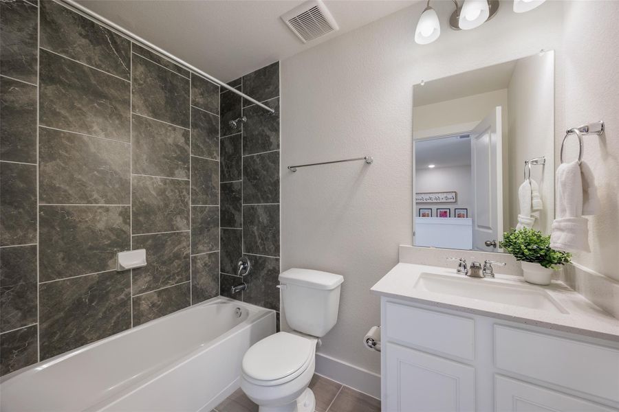Bathroom featuring vanity, shower / bath combination, tile patterned flooring, and a textured wall Bathroom featuring vanity, shower / bath combination, tile patterned flooring, and a textured wall