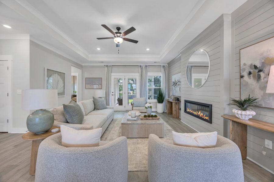 Living area featuring light wood-style floors, a large fireplace, a ceiling fan, wooden walls, and recessed lighting