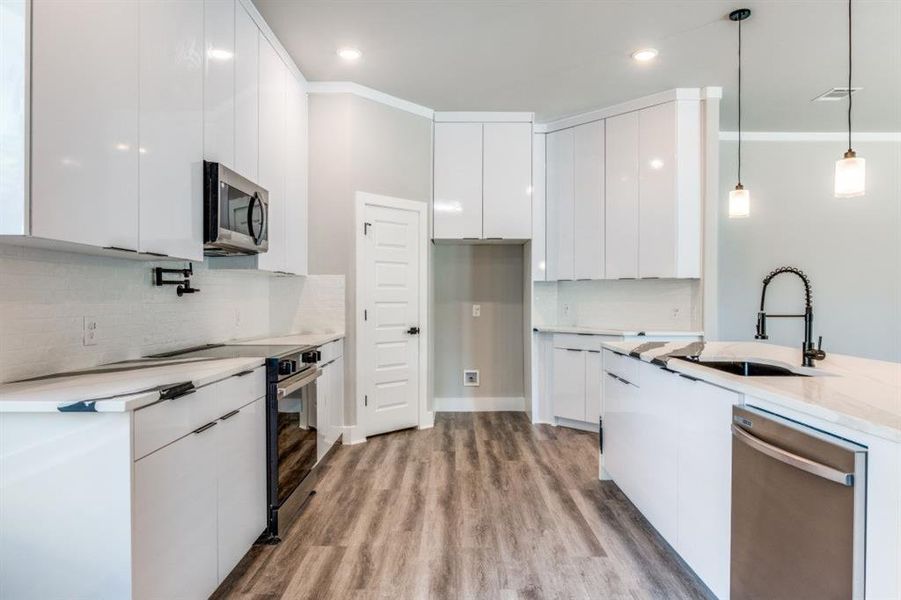 Kitchen with modern cabinets, pendant lighting, white cabinets, stainless steel appliances, and recessed lighting