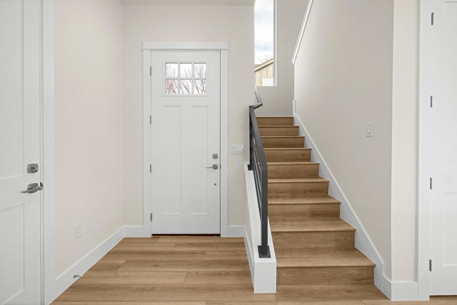 Foyer entrance featuring stairs and light wood-style flooring.