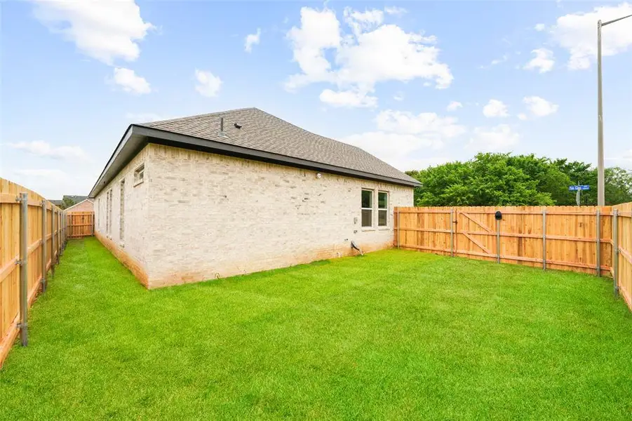 Expansive grassy yard enclosed by a wood privacy fence with a gated entry